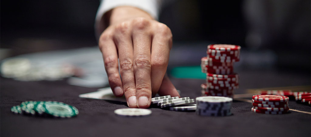 ręka z żetonami, stół kasynowy, gra w bakarata, hazard, strategia gry, eleganckie kasyno, emocje, rozgrywka na żywo