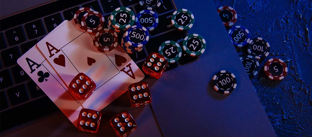 Kasyno online, laptop, karty asy, żetony pokerowe, kości do gry, ciemne tło, hazard, poker, blackjack, gra online, rozrywka